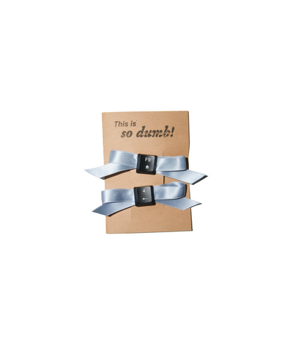 Pair of sky blue 100% silk bow hair clips with reclaimed keyboard keys, photographed on branded packaging. Handmade in-house in NYC.